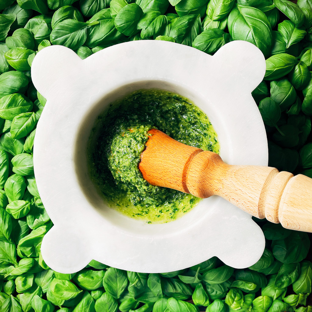 Basil pesto being made in a pestle and mortar.